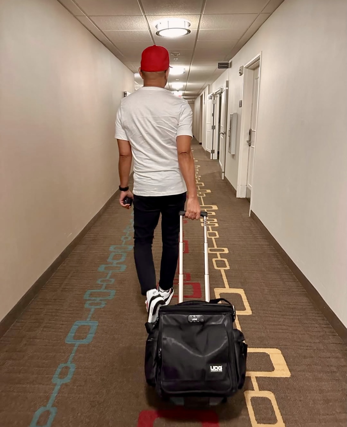 Decorative photo of Frank walking through a hotel room with a suitcase