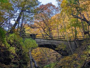 A concrete bridge among autumn trees at Matthiessen State Park in Illinois.