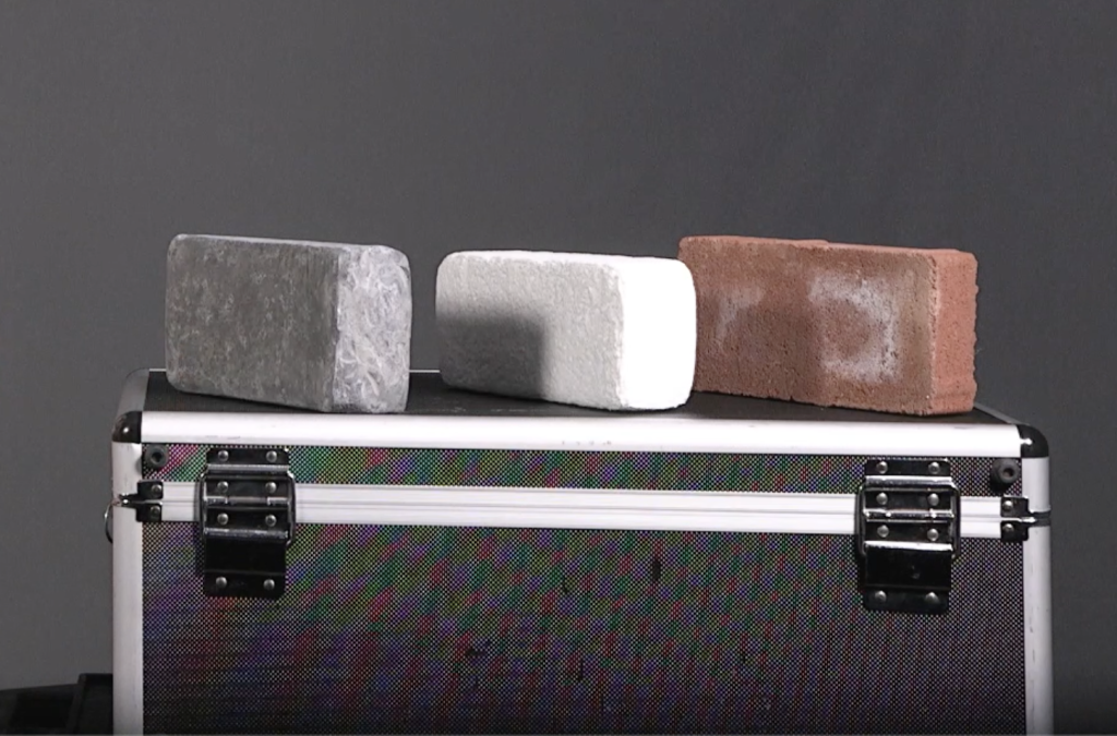 From left to right: a lead, styrofoam, and clay brick sitting on top of a chest.
