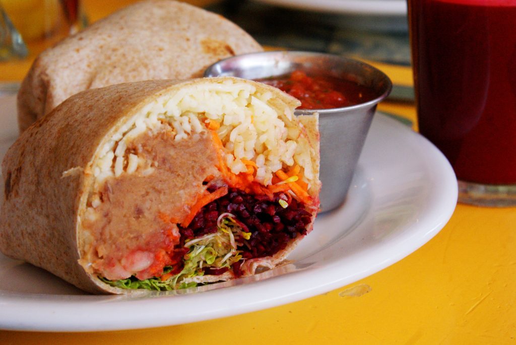 A photograph of a burrito containing rice, beans, carrots, and other vegetables.