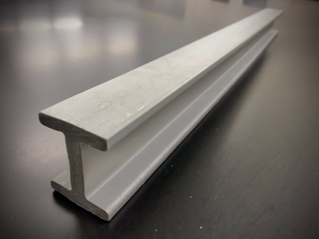 A photograph of a plastic i-beam as it rests on a black lab table.