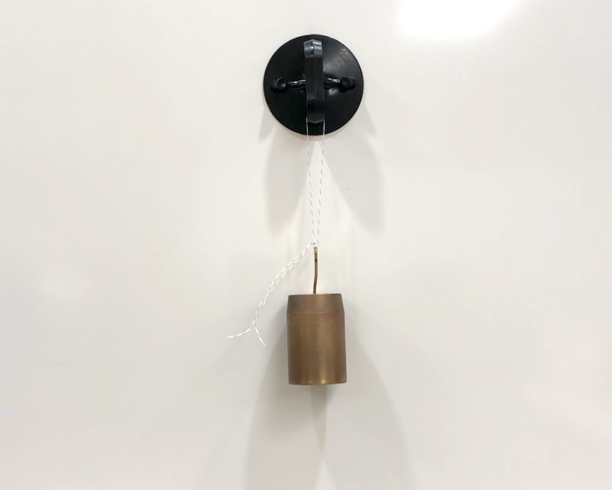 A photograph of a black suction cup stuck to a whiteboard. A piece of string is tied around the suction cup, and is supporting a 1 kg mass.