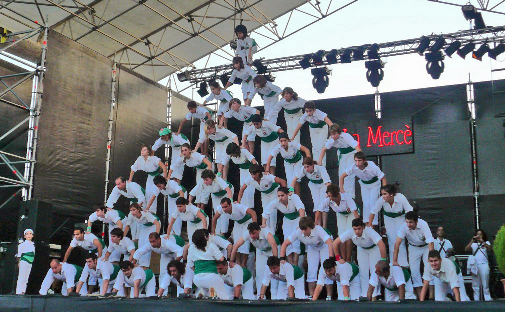 A photograph of about 50 people arranged in a human pyramid. There are many people at the base, and about 9 rows of people altogether.