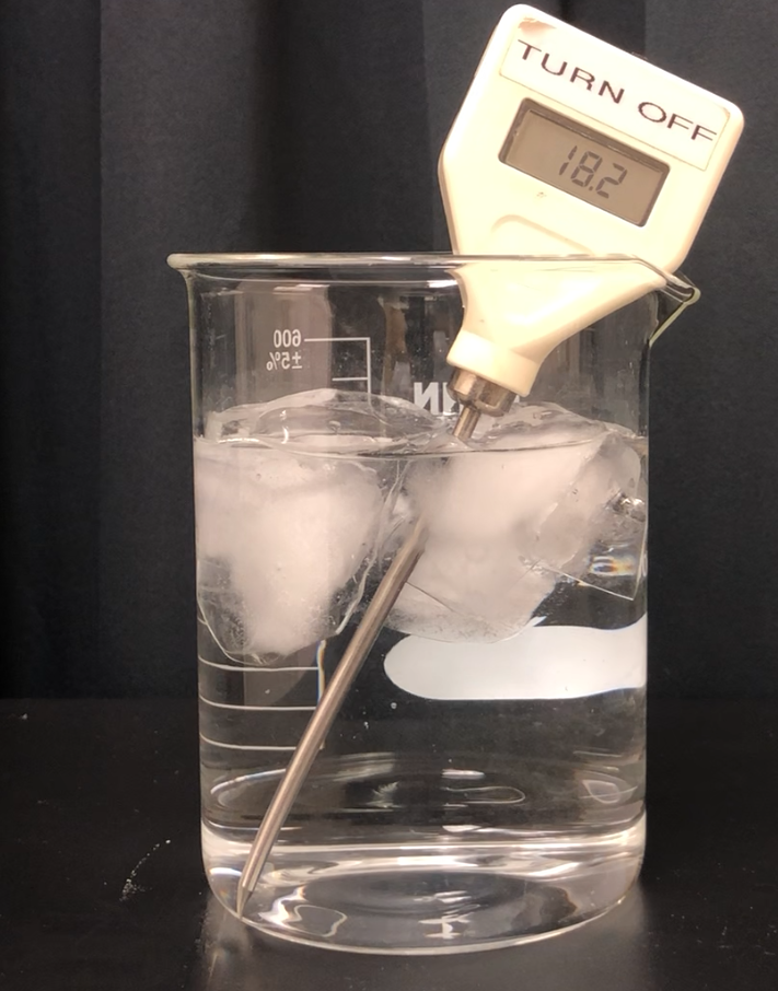 A digital thermometer is placed into a beaker of water with ice cubes in it. The temperature reading is 18.2 degrees celsius.