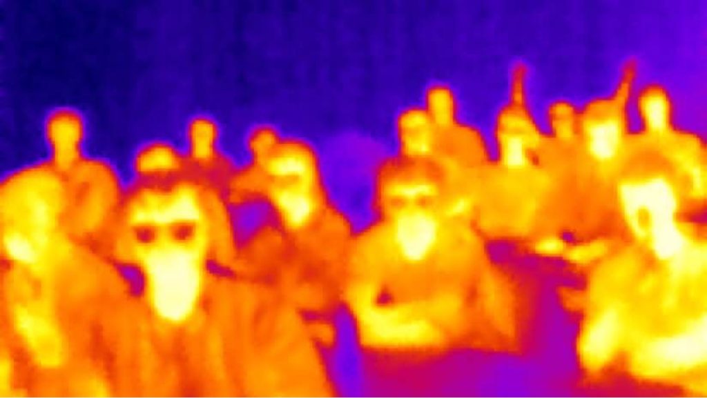 A photograph taken using infrared of students in a classroom. Students appear in shades of blue to red coloring, based on their temperature. Students with glasses appear to have black spots where their glasses are.
