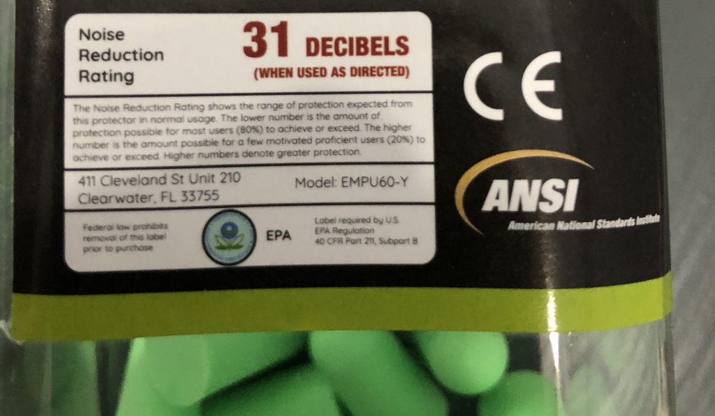 A photograph of a package of earplugs. Notably, the label contains text stating "Noise reduction rating: 31 decibels (when used as directed)."
