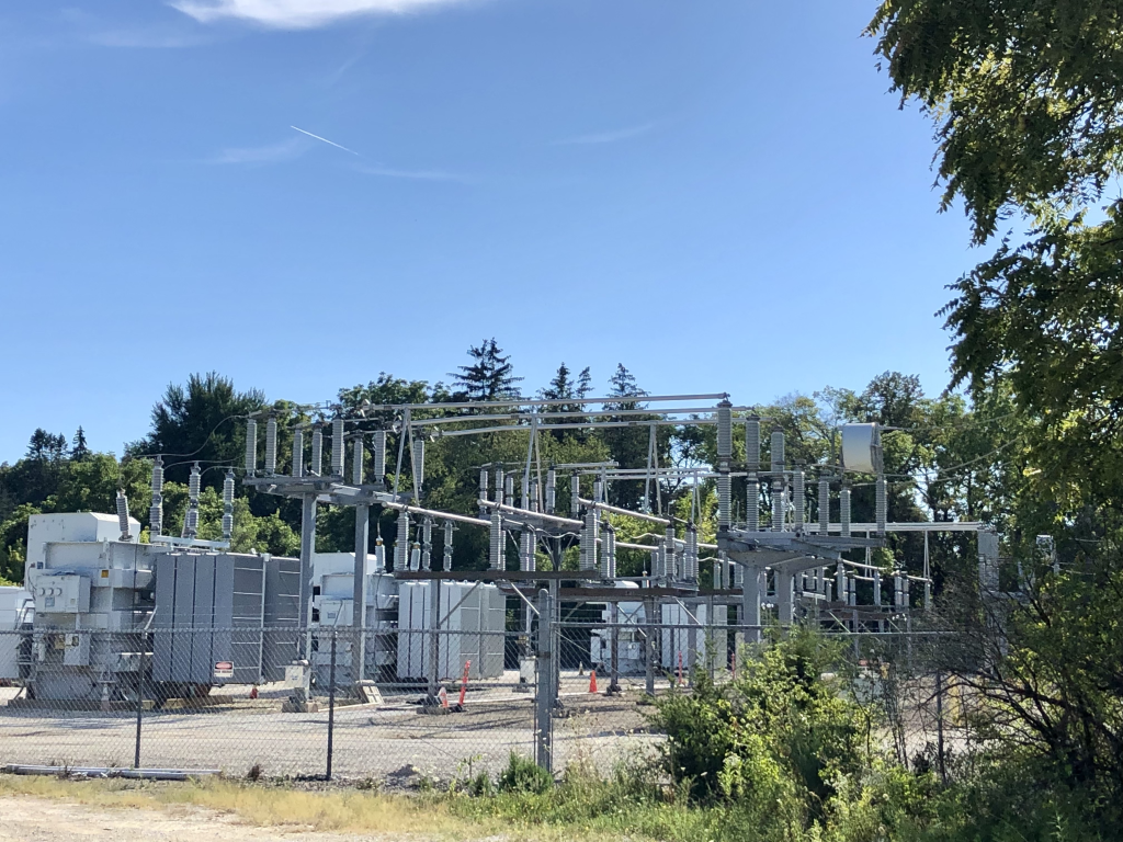 A photograph of an electrical substation surrounded by trees.