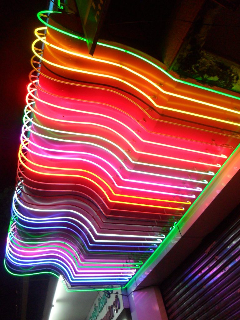 A photograph of a building containing stripes of different colored "neon" lighting.