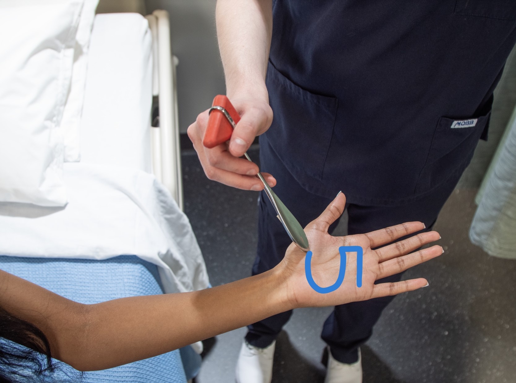 Nurse drawing a number five in the palm of a person's hand.