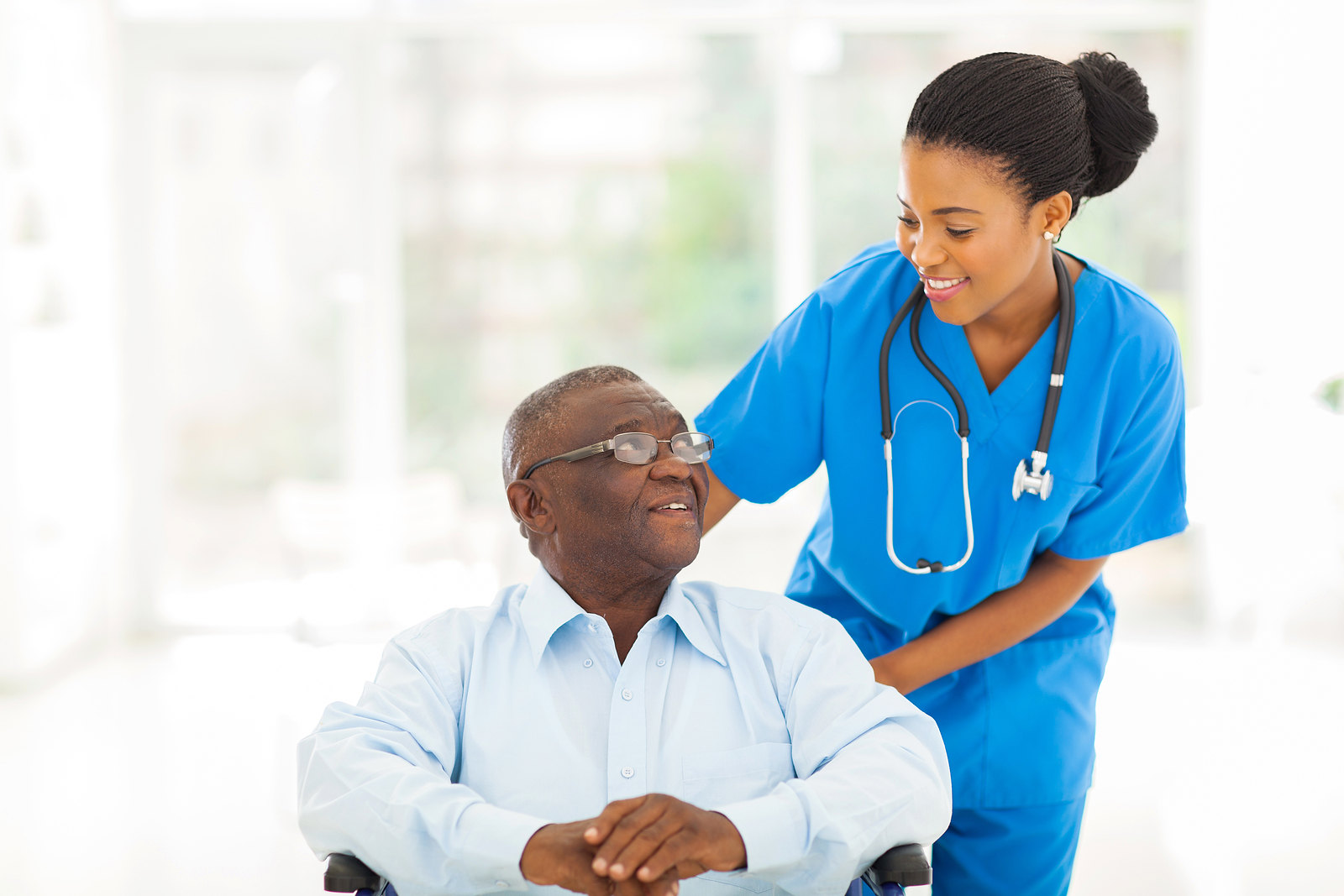 Photo of a female healthcare worker assisting an older patient in wheelchair