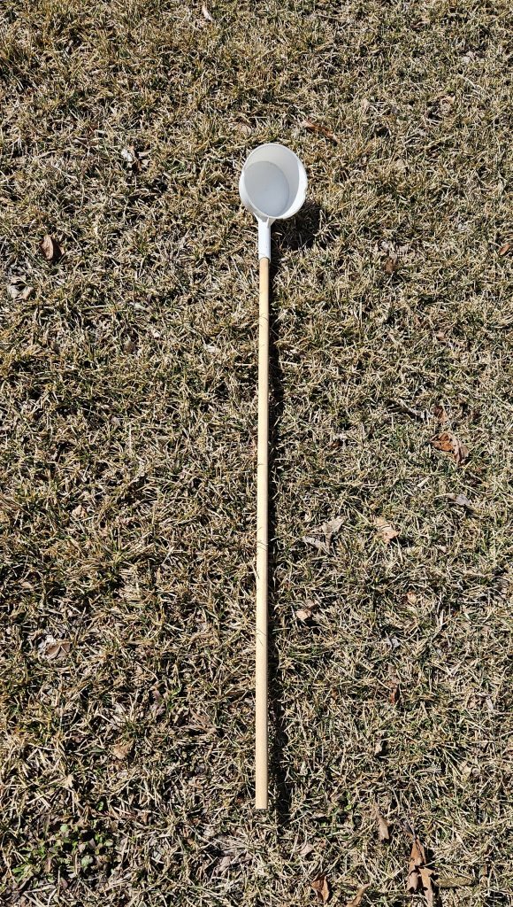 A long wooden pole with a small sampling cup at the end.