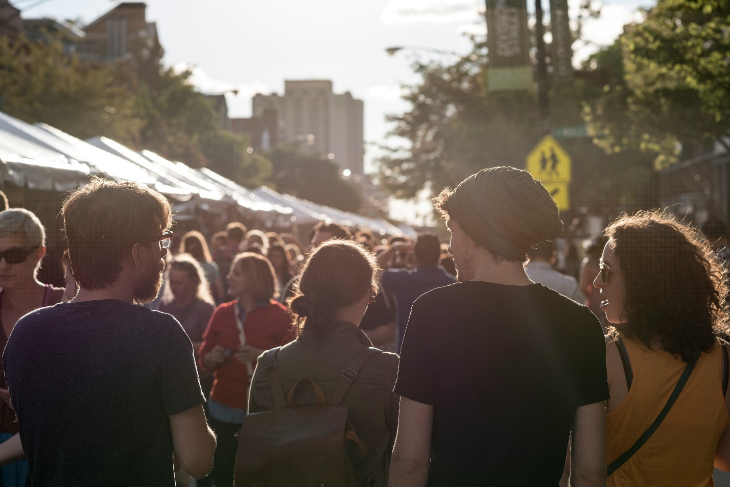 People walking next to tents during a street festival.