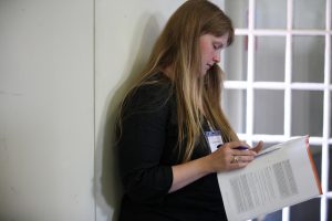 photo of a woman standing and reading some papers