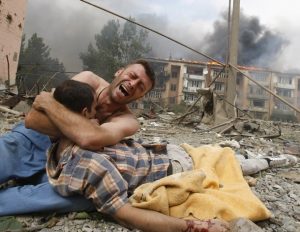 Photo of weeping man clutching dead body in urban wreckage in Gori in 2008.