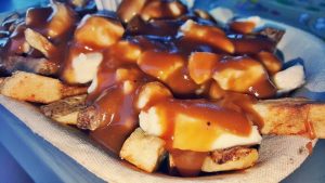 Photography of plate of poutine - fries, cheese, and gravy.