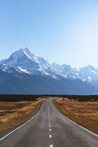 Photography of a long road approaching Mount Cook, New Zealand's highest peak.