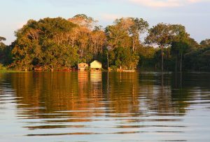 Photograph of small buildings along the broad Amazon River.