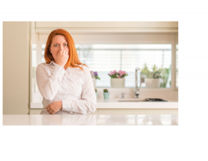 Woman in white holding her nose in a clean kitchen