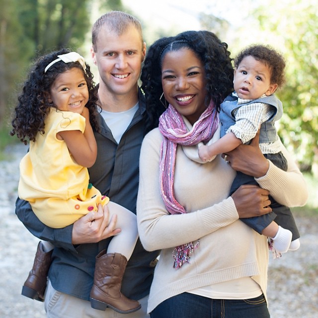 Color photograph of a bi-racial family. Dad, mother, and two children,
