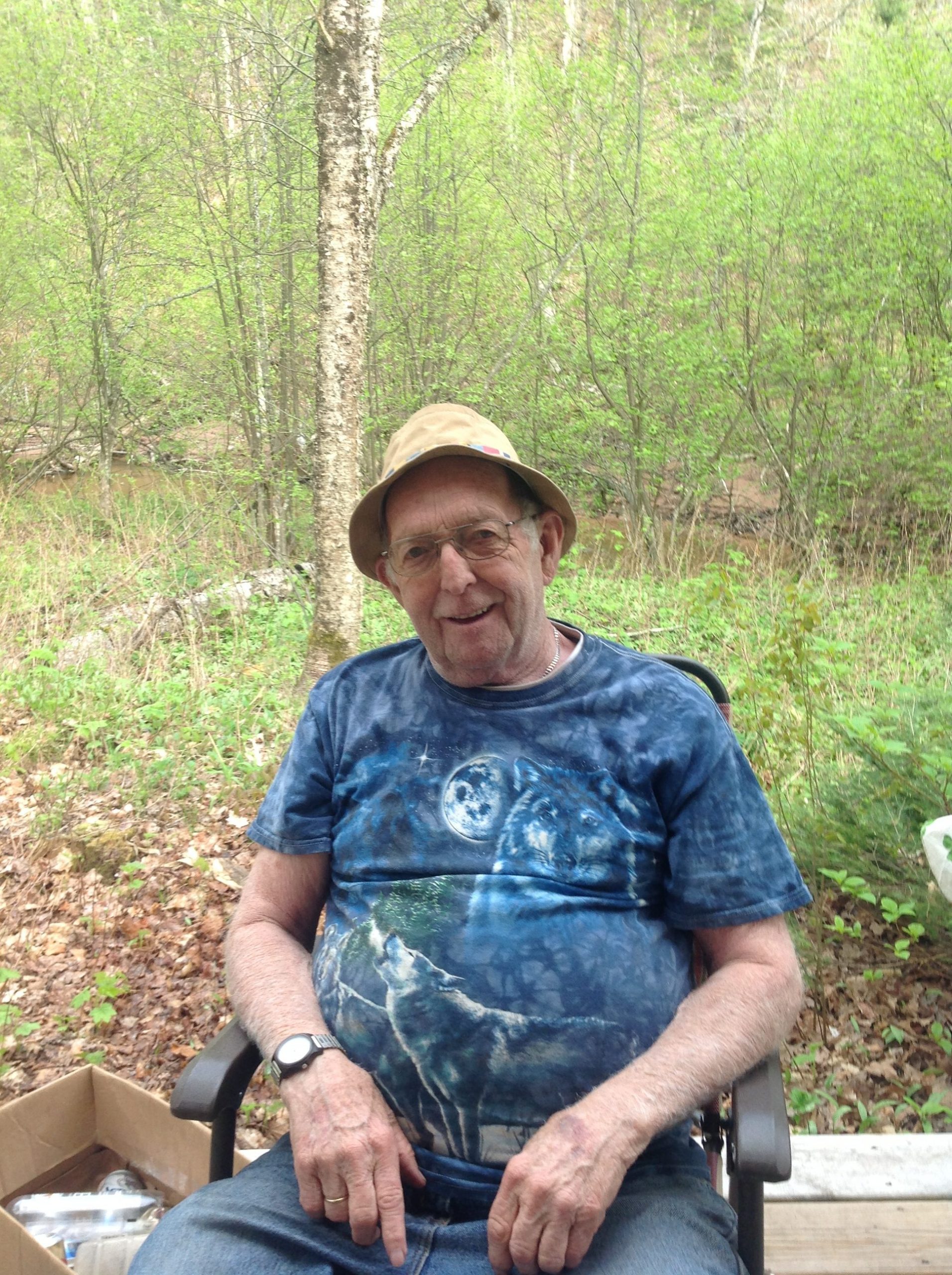 Picture for decorative purposes. Elderly man sitting in a chair out in the woods.