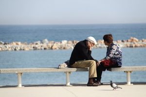 Picture for decorative purposes. It is an elderly couple sitting on a bench by the ocean.